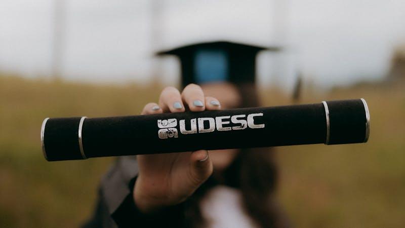 Jeune diplômée en toque et robe tenant son diplôme